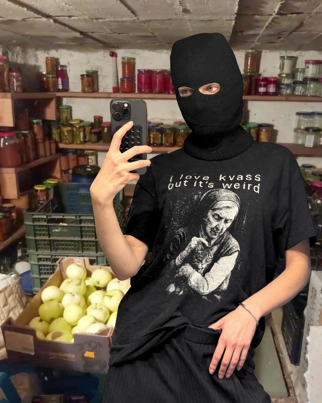 Person wearing a black balaclava and t-shirt with a graphic design in a store setting.