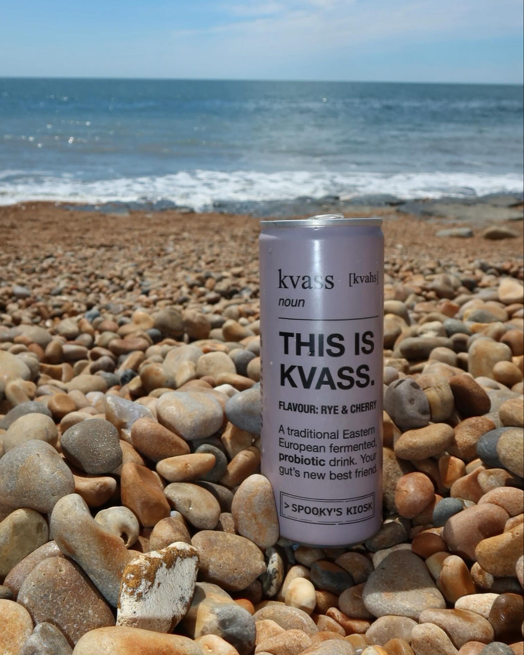 Can of kvass on pebbles with ocean and sky in the background