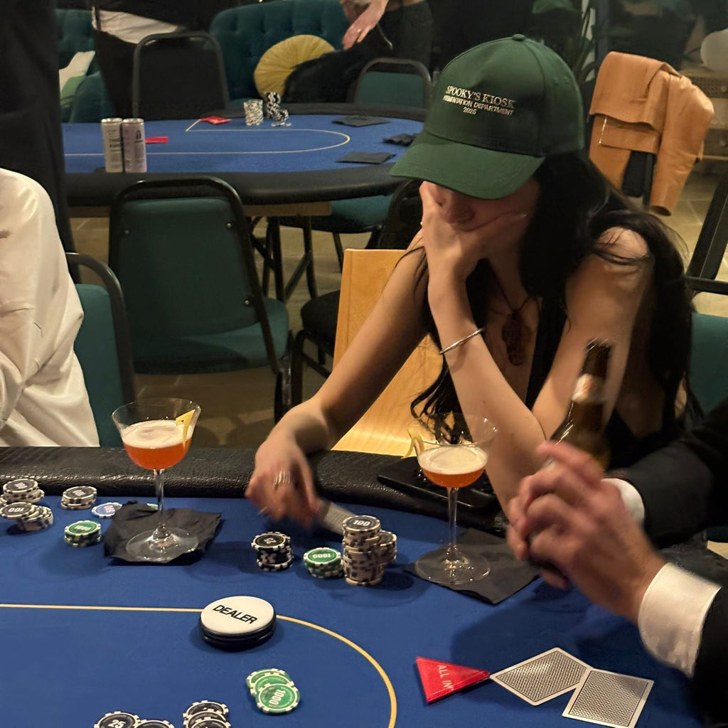 Person playing poker at a casino table with drinks and chips. kvass spooky's kiosk hat green