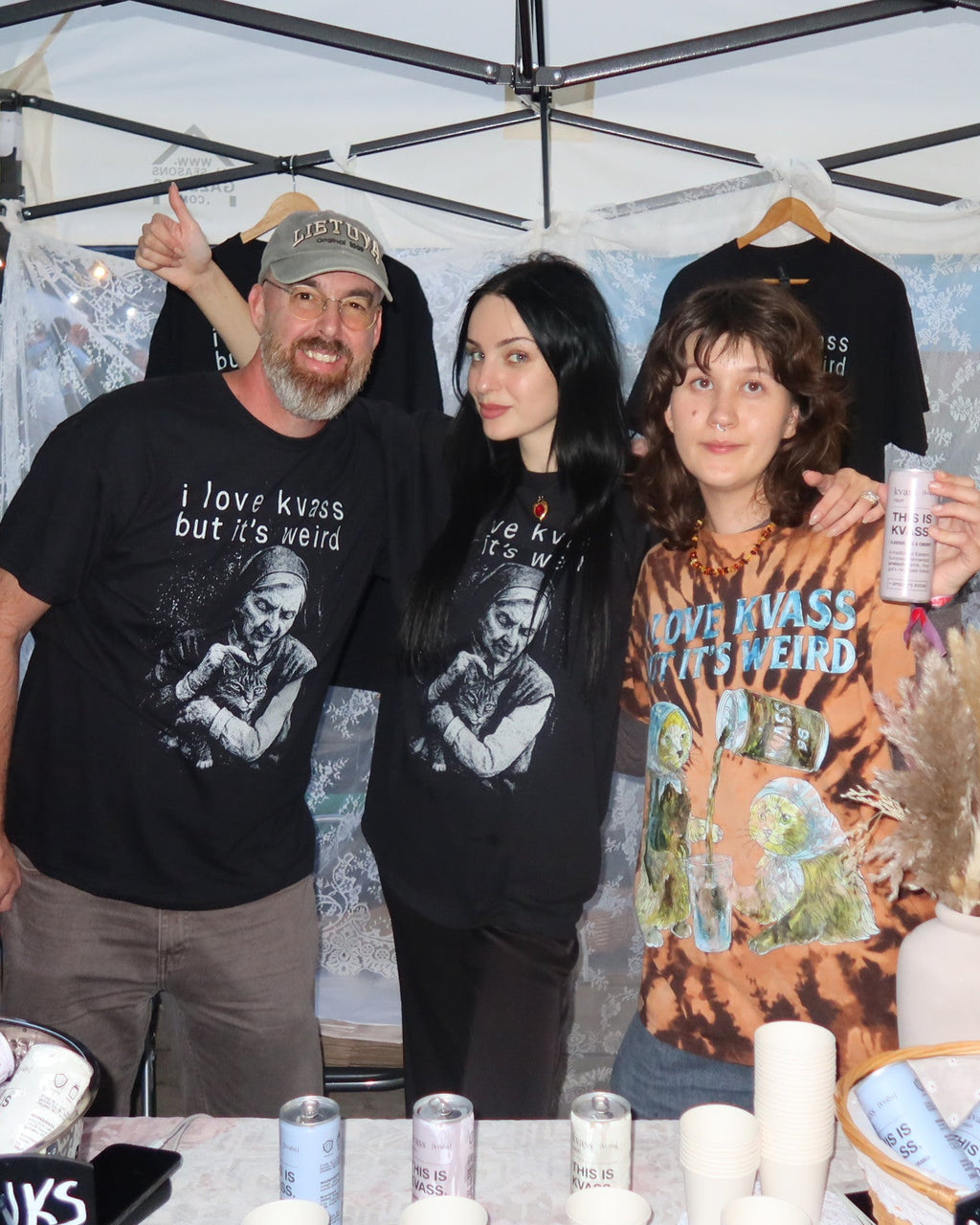 Three people posing under a white pop-up canopy tent at the big pine festival for spookys kiosk kvass 